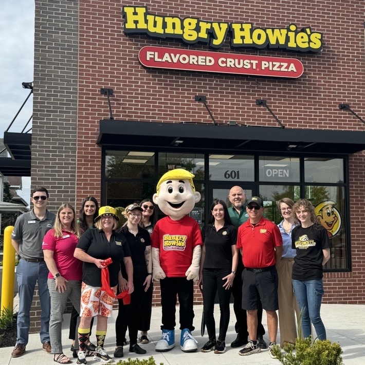 Hungry Howie's franchisee and employees smiling and standing in front of a franchise location during a grand opening event.