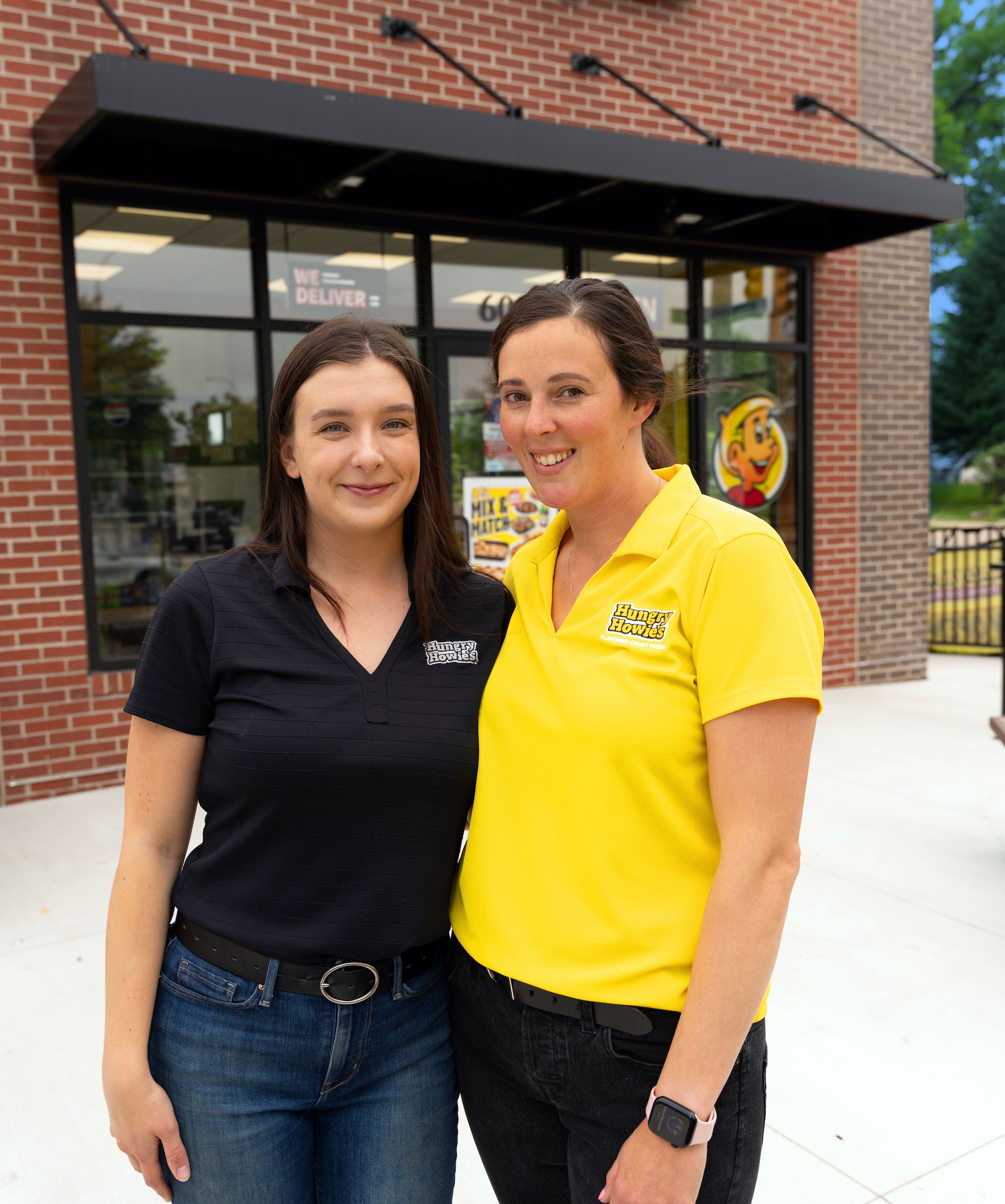 Two female hungry howie's franchise owners standing in front of their storefront smiling