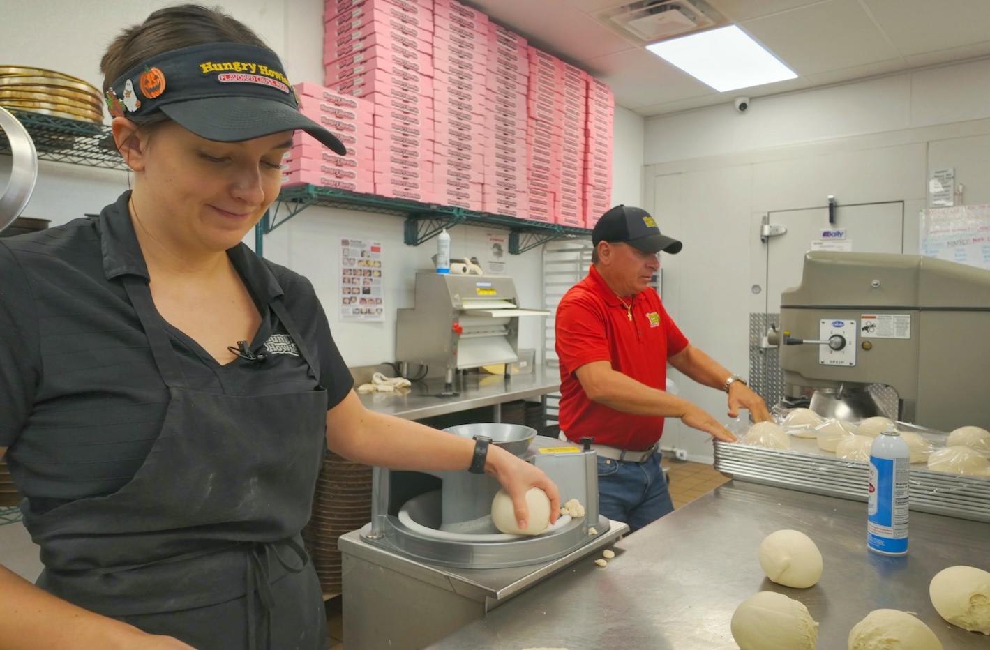 Two employees making pizza