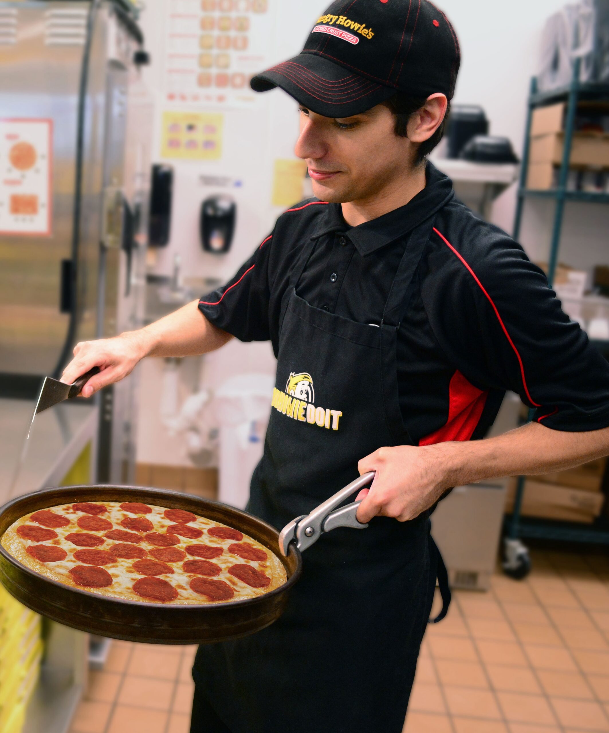 Employee making a pepperoni pizza