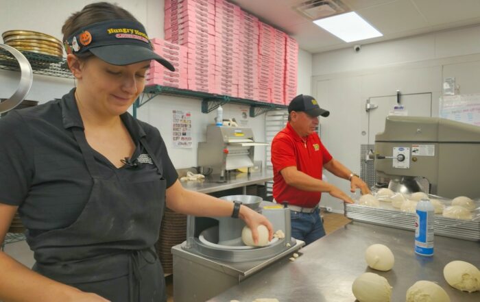 Two employees making pizzas