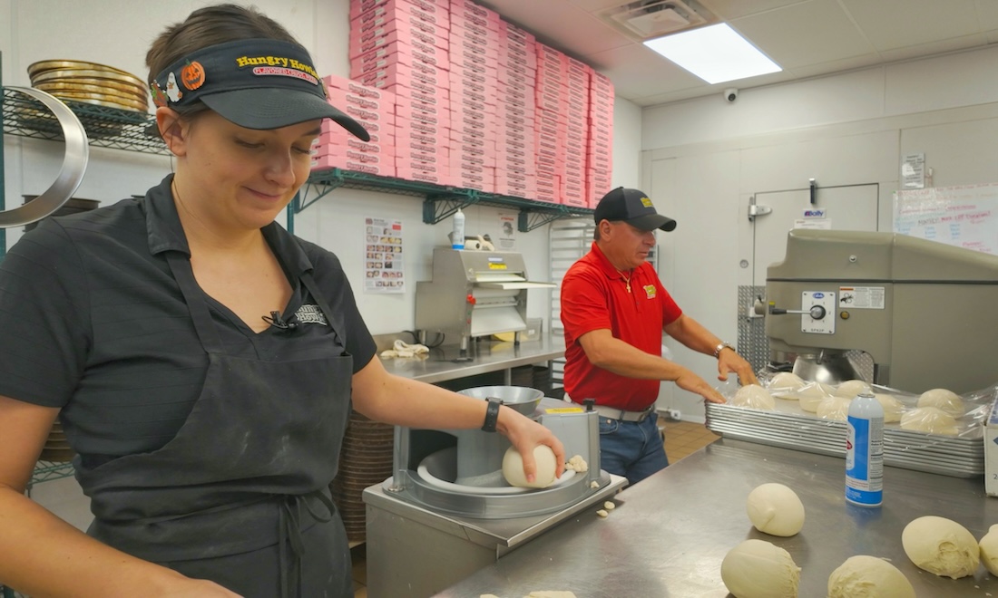 Two employees making pizzas