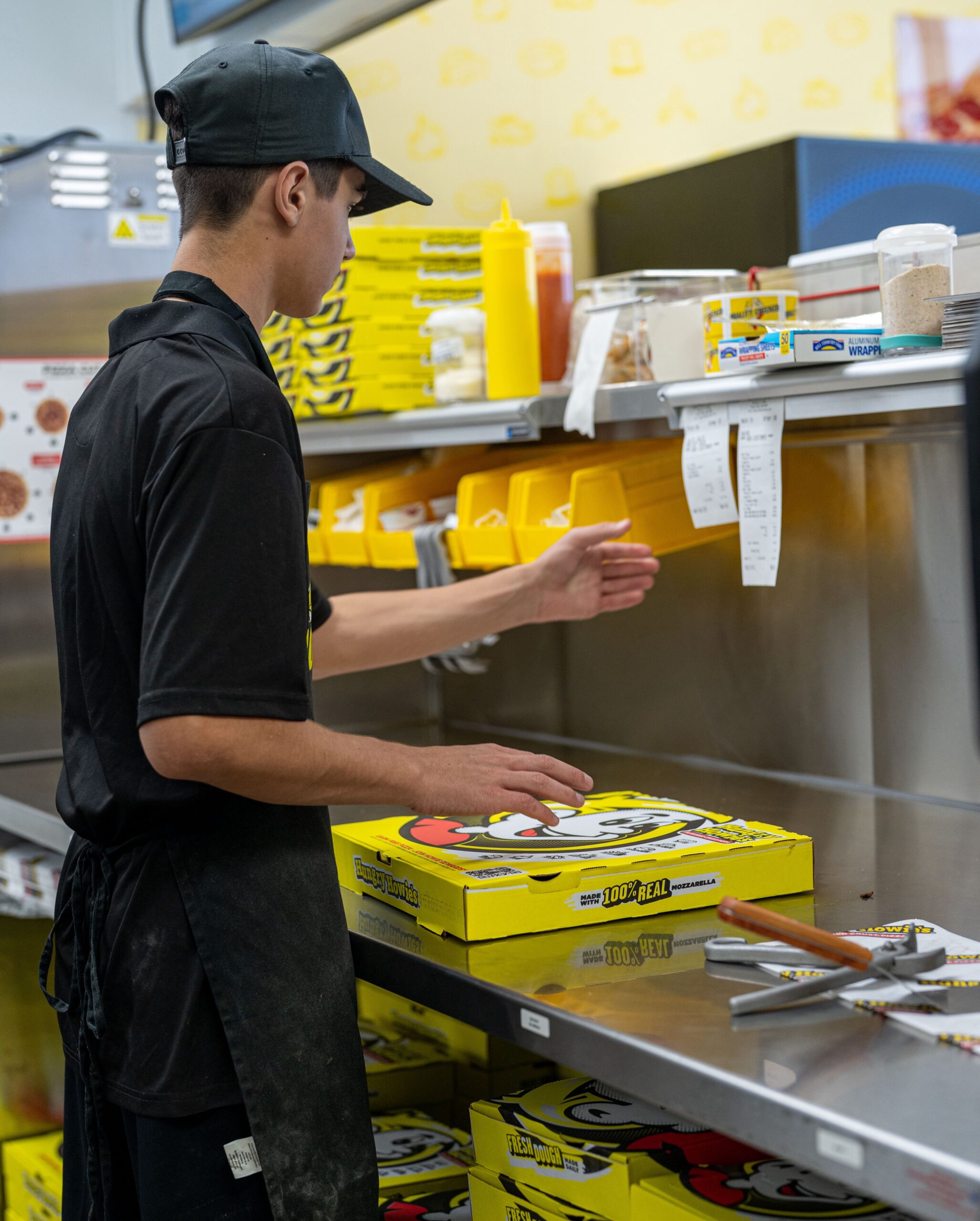 Young hungry howie’s employee in the kitchen looking at receipts Young hungry howie's employee in the kitchen looking at receipts