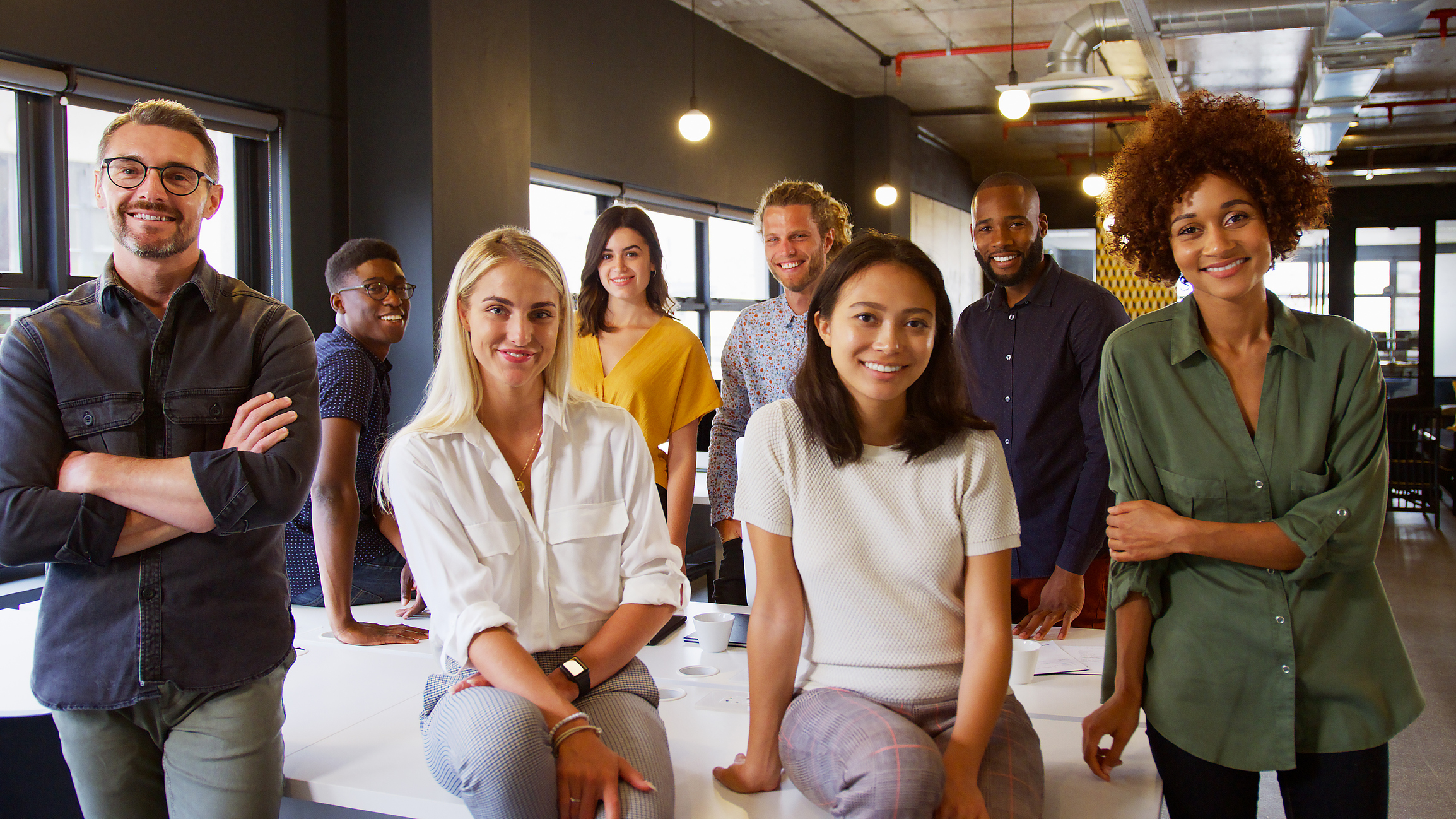 Portrait Of Smiling Multi-Cultural Business Team In Modern Open Plan Office Together